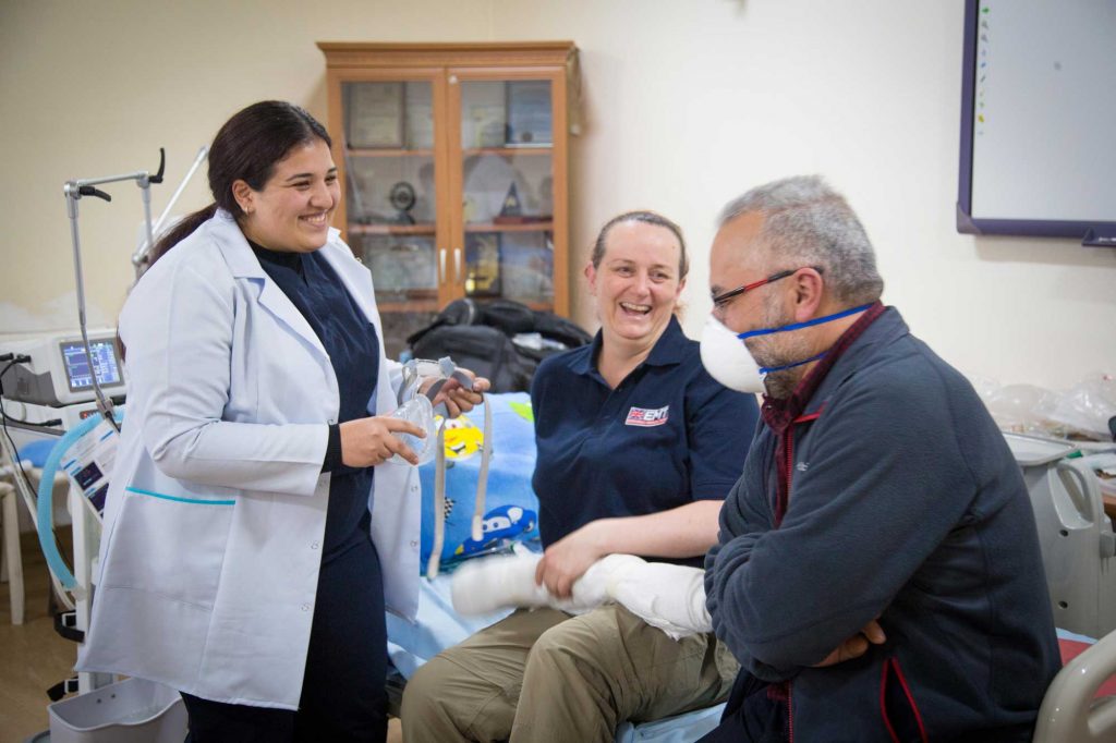 A British nurse and Armenian nurse are smiling and talking together with an interpreter during a training session.